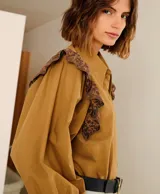 Camisa color marrón con cuello clásico, mangas largas abullonadas con puños elásticos y detalles de encaje floral en hombros y puños.