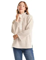 Buzo de tejido soft mohair con estampado zigzag en tonos beige y blanco. Presenta cuello polo, escote en V con botones a presión y manga larga amplia. El bajo tiene tajos laterales y apliques metálicos.