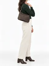 Cartera de cuero vacuno en color marrón, de diseño compacto, líneas simples y formato estructurado. Cuenta con correa corta ajustable para llevar al hombro y cierre superior.