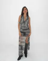 Vestido largo de fiesta con estampado abstracto en tonos grises y negros. Tiene escote halter con drapeado en el busto y abertura lateral en la falda.