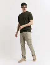 Pantalón de gabardina color marrón, de corte recto, con bolsillos laterales tipo cargo y bolsillos traseros con solapa.