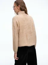 Sweater de cuello alto con textura peluda, confeccionado en tejido de punto suave y holgado, con mangas largas y puños ajustados.