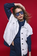 Chaleco de jean color blanco, de corte oversized, con cuello camisero, bolsillos delanteros con solapa y cierre frontal por botones metálicos.
