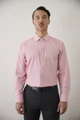 Camisa de vestir de manga larga con cuello clásico y cierre frontal de botones. Presenta un diseño de micro-rayas verticales en tono rosado.