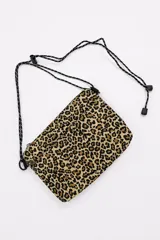 Bandolera pequeña con estampado animal print de leopardo, bolsillos frontales con cierre y correa ajustable de cordón negro con detalles blancos.