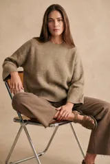 Sweater de lana de corte oversize, con cuello redondo y mangas largas con puños acanalados. Diseño de tejido liso en tono neutro.