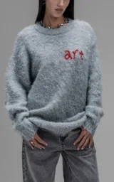 Sweater de punto texturizado color gris, con cuello redondo y diseño oversize. Presenta un bordado en relieve en la espalda con la frase 'art SUPPORT' en letras rojas y negras.