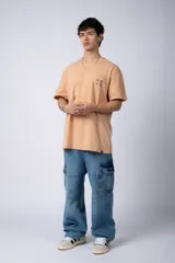 Remera de corte semi-oversize en color naranja con efecto de lavado tipo snow. Presenta un pequeño estampado gráfico en el pecho y cuello redondo.