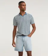 Bermuda de jean corte loose, color azul claro con lavado desgastado, cuenta con bolsillos laterales y traseros, cierre frontal con botón y bragueta, y pasacintos.