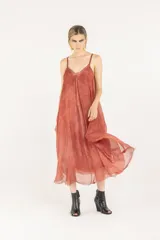 Vestido midi lencero de viscosa y seda, color salmón, con breteles regulables, escote en V, silueta evasé con vuelo, bolsillos laterales y ruedo deshilachado.