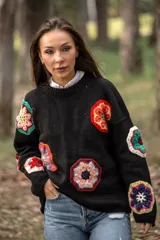 Sweater negro de lana con cuello redondo y apliques de flores de crochet multicolores.