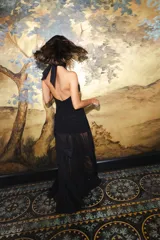 Vestido largo de encaje y transparencias color marrón, con escote profundo halter, frunces en el cuerpo, espalda abierta y tiras largas estampadas para atar al cuello.