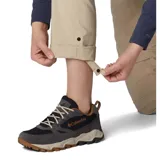 Pantalón convertible de mujer, color beige, diseñado para actividades al aire libre. Presenta un corte recto, bolsillos laterales y traseros, y perneras desmontables mediante cremallera que permiten transformarlo en shorts.