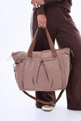 Bolso tipo shopper de nylon color negro, con diseño amplio y liviano. Cuenta con asas reforzadas, cierre superior y bolsillos frontales con frunces y cierre, ofreciendo gran capacidad y organización.