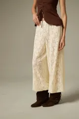 Pantalón tipo babucha de encaje color crudo, con corte holgado y cintura elástica.