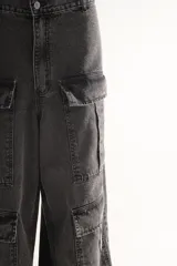 Pantalón jean cargo wide leg color gris oscuro, de tiro medio/bajo con pierna y bota ancha. Tiene cuatro bolsillos grandes en las piernas y largo a los tobillos.