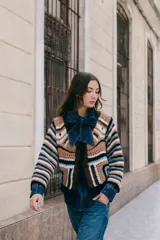 Saco tejido en crochet con diseño de rayas horizontales en mangas y espalda. Presenta un cierre frontal con lazos de crochet en el escote en V y detalle de flecos en el ruedo.