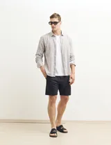 Camisa de lino a rayas verticales color beige y blanco, de corte clásico, con cuello abotonado y mangas largas.