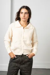 Saco de punto color blanco con cuello tipo polo, cierre frontal con botones y diseño de flores bordadas en relieve. Posee mangas largas con puños acanalados y ruedo elástico.