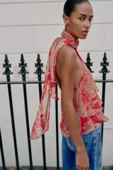 Top rojo con estampado estilo paisley, diseño de cuello halter con lazo, espalda descubierta y detalles de volantes en capas en el frente.