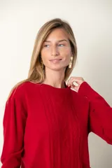 Sweater rojo de punto con cuello redondo, mangas largas, trenzado central y bolsillos delanteros.
