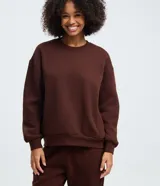 Buzo básico de cuello redondo y manga larga, confeccionado en tejido de algodón con felpa. Presenta diseño liso sin estampados y puños y ruedo ajustados con elástico.