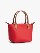 Cartera tote Tommy Hilfiger de nailon rojo, con dos asas superiores en tono tostado y una correa de mano o hombro tejida extraíble. Cuenta con cierre de cremallera superior, compartimento principal e insignia metálica con el monograma TH en el frente.