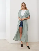 Kaftan largo color verde salvia, con mangas cortas y detalle de puntilla bordada en el área del busto y cintura. Posee un lazo ajustable en el centro del frente.