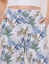 Pantalón crop de lino y rayón, con diseño wide leg de corte holgado, estampado tropical de hojas en tonos verde, azul y marrón sobre fondo blanco. Cuenta con pretina trasera elastizada y bolsillos delanteros.