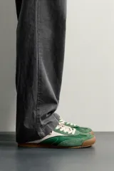 Zapatilla deportiva de estilo retro en color verde, confeccionada en una combinación de piezas de cuero y gamuza, con detalles a contraste en tono tostado y suela de goma dentada.