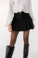 Falda corta tipo balloon color blanco, con cintura alta y diseño con volumen. Presenta una pequeña placa metálica con el logo de la marca en la parte frontal.