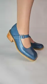 Guillerminas de cuero legítimo color azul, con puntera cuadrada, taco bajo de madera y tira con hebilla ajustable en el empeine.