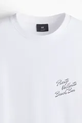Remera blanca de punto de algodón, cuello redondo con ribete acanalado, hombros caídos y corte holgado. Cuenta con pequeño estampado tipográfico en el pecho con la inscripción "Puerto Vallarta Beach Bar".