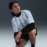 Camiseta de fútbol Nike Total 90 con diseño de rayas verticales celestes y blancas. Presenta cuello en V, mangas cortas y el logo circular T90 impreso en el centro del pecho junto con el swoosh de Nike en el lateral superior derecho.