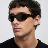 Lentes de sol envolventes con montura negra de diseño oversize y cristales color marrón. Presentan una silueta inspirada en los años 2000 con protección UV400.