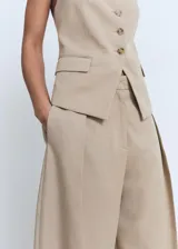 Pantalón de tiro medio color beige con diseño balloon y pinzas en la parte delantera. Cuenta con bolsillos laterales y cierre oculto.