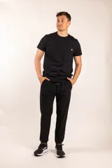 Pantalón de jogging negro con cintura elástica y cordón ajustable, bolsillos laterales con cierre y corte ajustado.