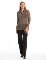 Camisa de tejido plisado y translúcido con hilos de lurex, de corte recto y manga larga. Presenta cuello con solapas, cierre frontal con botones y tajos laterales pronunciados en el bajo.