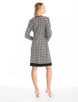 Vestido midi de tejido de punto con diseño integrado que simula un conjunto de vestido negro liso con un cárdigan largo estampado de eslabones geométricos en blanco y negro. Presenta escote redondo y mangas largas.