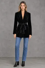 Blazer negro de terciopelo con hombreras, solapas cruzadas, bolsillos con solapa y lazo ajustable en la cintura.