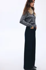 Pantalón de jean color azul marino, de tiro alto y corte wide leg, con amplios bolsillos frontales de parche y presillas para cinturón.