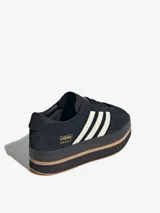 Zapatillas Adidas Gazelle Stack para mujer, color negro con las tres tiras laterales en blanco y suela de plataforma en color caramelo.