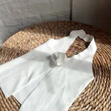 Top blanco con escote halter y detalle de flor en el centro.