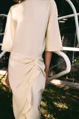Vestido midi de Zara Woman Collection, confeccionado en mezcla de viscosa, con cuello redondo, manga corta y detalle de drapeado lateral con volado. Presenta bajo asimétrico y cierre en la espalda.