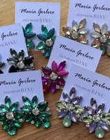 Par de caravanas con forma de flor, con pétalos de diferentes tamaños y colores: fucsia, violeta y rojo. En el centro tienen un cristal facetado y pequeños strass blancos.