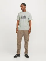 Remera color verde claro de manga corta y cuello redondo con estampado en el pecho con el logo de la marca Jack & Jones y un diseño abstracto en tonos grises y negros.