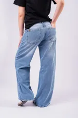 Pantalón de jean tiro bajo con corte wide leg y lavado celeste vintage. Presenta un diseño de pernera ancha y recta, con cierre de botón y cremallera, y bolsillos laterales y traseros.