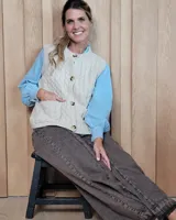 Chaleco de punto con diseño de trenzas, color gris oscuro, con cierre frontal de botones grandes y bolsillos laterales.