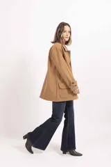 Chaqueta de paño color tostado, con cuello camisero, cierre frontal de botones y dos bolsillos delanteros con solapa.