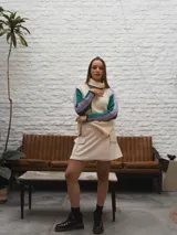 Buzo tejido de punto color crema con cuello alto y mangas largas con rayas horizontales en verde y lila.